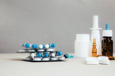 Şişelerde ve tabletlerde, şeffaf plakalarda hafif arka planda tedavi için bir takım ilaçlar. Ön görünüm