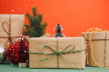 Selamlaşmak için arka plan. Kahverengi kağıda sarılan hediyeler kırmızı-yeşil arka planda. Ön görünüm