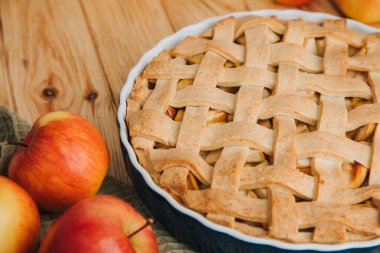 Elmalı turta açık ahşap arka planda, yeşil mutfak havlusuyla mavi formda. Hazır turta. Üst görünüm