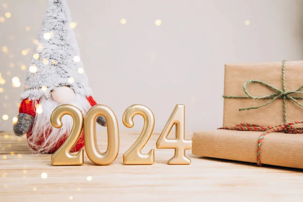 Boşluklu selamlama arkaplanı. Mutlu yıllar kartı. Noel cücesiyle birlikte açık ahşap arka planda 2024 'e benziyor. Ön görünüm