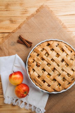 Elmalı turta açık ahşap arka planda beyaz mutfak havlusuyla mavi formda. Hazır turta. Üst görünüm