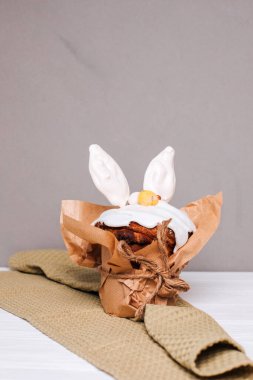 Paskalya pastası, açık arkaplanda beyaz kulaklı kremalı ve çikolatalı yumurtalarla süslenir. Paskalya arkaplanı, kutlama masası hazırlıkları. Ön görünüm