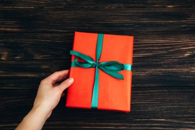 Noel, şenlikli bir geçmiş. Kırmızı kağıda sarılı hediyeler, kadınların elinde yeşil kurdele, siyah tahta arka planda. Üst görünüm