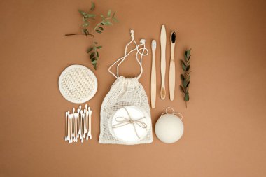 Çevreye dost banyo cihazları kurun. Çamaşır bezleri ve yüz süngeri, kulak çubukları ve kahverengi arka planda bambu diş fırçaları. Düz yatıyordu