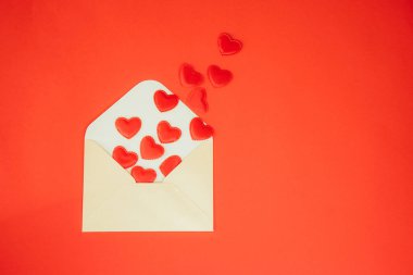 Kırmızı arka planda kırmızı kalpler olan açık yeşil bir zarf. Sevgililer Günün kutlu olsun, geçmiş. Düz yatıyordu