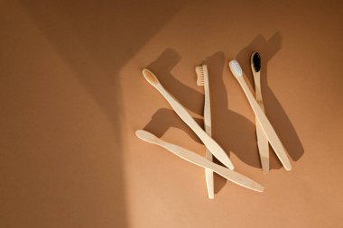 Tahta, bambu diş fırçaları kahverengi arka planda, gölgeli. Çevre dostu ürünler. Düz yatıyordu
