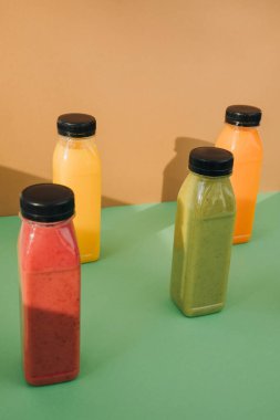 Şeffaf plastik şişelerde meyve ve sebze içecekleri. Kahverengi-yeşil arka planda kırmızı, yeşil, turuncu meyve püresi. Sağlıklı beslenme kavramı. Üst görünüm