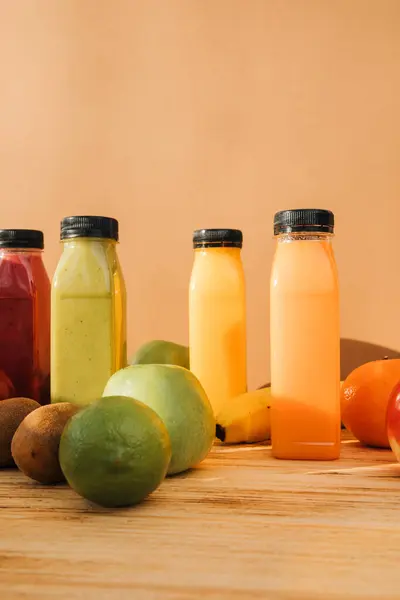 Fruit and vegetable smoothies in transparent plastic bottles. Red, green, orange smoothies on a wooden table. The concept of healthy eating. Front view
