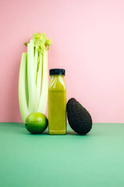 Fruit and vegetable smoothies in transparent plastic bottles. Green smoothie on a pink-green background with avocado and celery. The concept of healthy eating. Front view