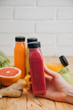 Şeffaf plastik şişelerde meyve ve sebze içecekleri. Ahşap bir masada kırmızı, yeşil, turuncu meyve püresi. Sağlıklı beslenme kavramı. Ön görünüm