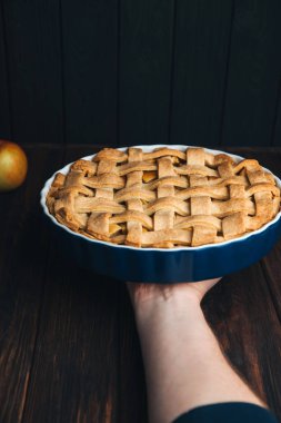 Elmalı turta mavi formda, erkek eli koyu ahşap arka planda. Hazır turta. Ön görünüm