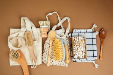 Farklı ahşap fırçalar ve kahverengi arka planda ahşap çatal bıçaklarla depolamak için bej ağlı çanta. Çoklu kullanım ve bilinçli tüketim için yankı torbaları. Düz yatıyordu