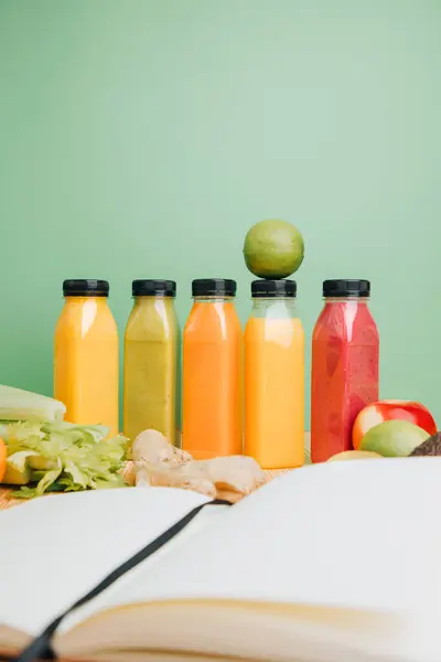 Fruit and vegetable smoothies in transparent plastic bottles. Green, red, orange smoothies on a green and wooden background. The concept of healthy eating. Front view