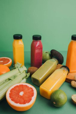 Şeffaf plastik şişelerde meyve ve sebze içecekleri. Yeşil arka planda kırmızı, yeşil, turuncu meyve püresi. Sağlıklı beslenme kavramı. Web afişi. Üst görünüm