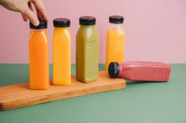 Şeffaf plastik şişelerde meyve ve sebze içecekleri. Yeşil, kırmızı, turuncu smoothie pembe-yeşil arka planda. Sağlıklı beslenme kavramı. Ön görünüm