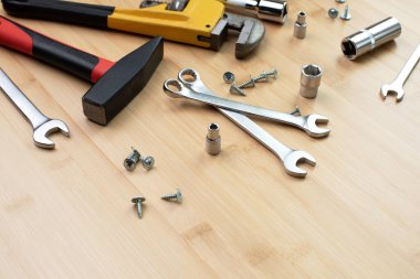 Bir takım çalışma aletleri, bir çekiç, bir tornavida, ayarlanabilir anahtarlar, bambudaki tamir için soketler, ahşap arka plan. Düz yatıyordu