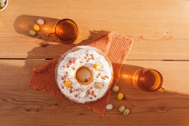 Mutfakta paskalya keki hazırlama süreci. Protein jöleli yuvarlak Paskalya pastası ve iki fincan çayla dekoratif tatlı bardaklar hazır. Üst görünüm