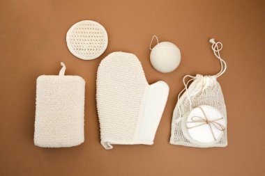 Çevreye dost banyo cihazları kurun. Kahverengi arka planda çamaşır ve yüz süngeri. Düz yatıyordu