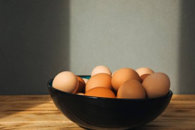 Farklı kahverengi ve bej renkte tavuk yumurtaları ahşap bir masada büyük bir kasede. Paskalya geçmişi. Ön görünüm