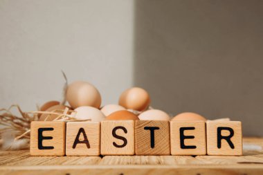 Paskalya arkaplan esprisi harfli tahta küpler. Mutlu Paskalyalar. Tahta bir masada farklı kahverengi ve bej tonlarda tavuk yumurtaları. Ön görünüm.