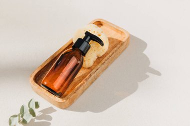 Doğal kozmetik seti. Yüz bakımlı kehribar şişeleri, beton zeminde banyo sıvısı ve doğal banyo süngeri. Üst görünüm