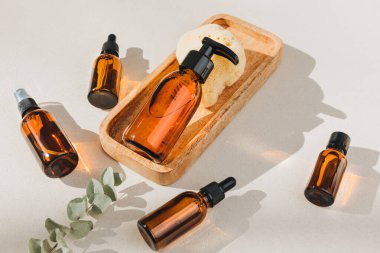 Doğal kozmetik seti. Yüz bakımlı kehribar şişeleri, beton zeminde banyo sıvısı ve doğal banyo süngeri. Üst görünüm