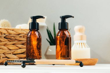 Doğal kozmetik seti. Yüz bakımlı kehribar şişeleri, beton arka planda banyo sıvısı ve doğal fırçalar. Ön görünüm