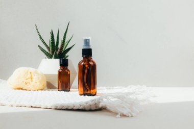 Doğal kozmetik seti. Yüz bakımlı kehribar şişeleri, beton zeminde banyo sıvısı ve doğal banyo süngeri. Ön görünüm