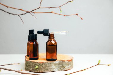 Doğal kozmetik seti. Yüz bakımı yapılmış kehribar şişeleri, beton arka planda banyo sıvısı ve ağaç dalları. Ön görünüm