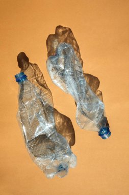 Kahverengi arka planda sudan gelen boş şeffaf plastik şişeler. Platsik 'siz bir gezegen, çöp. Sürdürülebilir kullanım. Üst görünüm