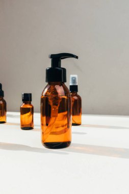 Doğal kozmetik seti. Yüz bakımı yapılmış kehribar şişeleri, beton arka planda banyo sıvısı. Ön görünüm