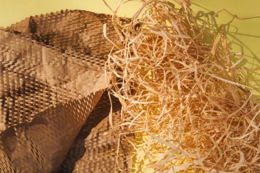 Ekolojik malzemelerin ambalajı. Ambalaj kağıdı ve dekoratif kutu doldurucu, sarı arka planda kuru saman. Gezegeni tespit edilemeyen enkazlardan kurtarmak. Üst görünüm