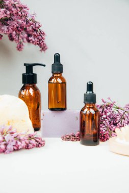 Kozmetik ürünleri olan şişeler ve beton arka planda leylak çiçekli doğal sabunlar. Doğal malzemelerden kozmetik ürünler, bitki. Ön görünüm