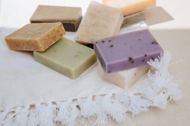 Doğal malzemelerden elde edilen el yapımı sabun, beyaz havluda çeşitli otlar. Sürdürülebilir kullanım kavramı, banyo ürünleri. Üst görünüm