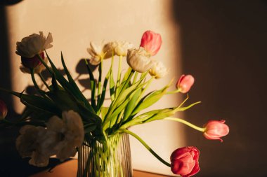 Ahşap masadaki vazoda beyaz ve pembe laleler. Bir buket çiçekle bahar arkaplanı. Ön görünüm