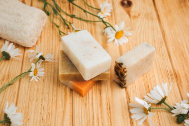 Doğal malzemelerden elde yapılan sabun, çeşitli otlar, papatya çayı. Sürdürülebilir kullanım kavramı, ahşap zeminde banyo ürünleri. Üst görünüm