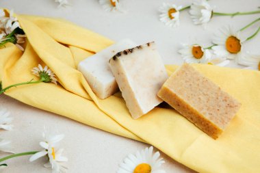 Doğal malzemelerden elde yapılan sabun, çeşitli otlar, papatya çayı. Sürdürülebilir kullanım kavramı, sarı havluda banyo ürünleri. Üst görünüm