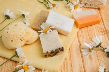Doğal malzemelerden elde yapılan sabun, çeşitli otlar, papatya çayı. Sürdürülebilir kullanım kavramı, sarı havluda banyo ürünleri. Üst görünüm