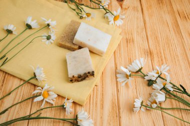 Doğal malzemelerden elde yapılan sabun, çeşitli otlar, papatya çayı. Sürdürülebilir kullanım kavramı, sarı havluda banyo ürünleri. Üst görünüm