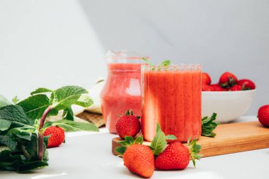 Şeffaf bardaklarda meyve suyu. Beton arka planda kırmızı çilekli smoothie. Sağlıklı beslenme kavramı. Ön görünüm