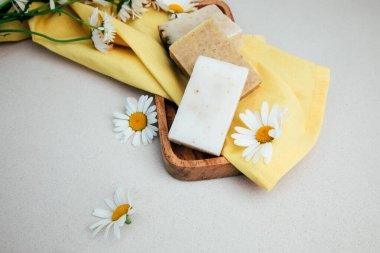 Doğal malzemelerden elde yapılan sabun, çeşitli otlar, papatya çayı. Sürdürülebilir kullanım kavramı, sarı havluda banyo ürünleri. Üst görünüm