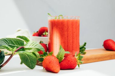 Şeffaf bardaklarda meyve suyu. Beton arka planda kırmızı çilekli smoothie. Sağlıklı beslenme kavramı. Ön görünüm