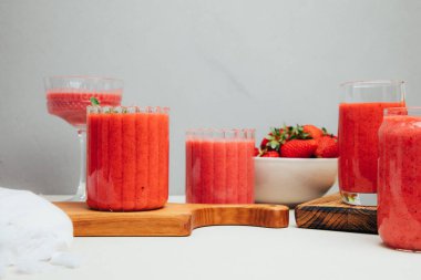 Şeffaf bardaklarda meyve suyu. Beton arka planda kırmızı çilekli smoothie. Sağlıklı beslenme kavramı. Ön görünüm