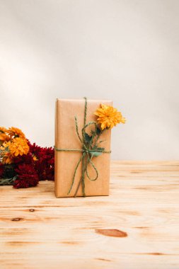 Çiçek arkaplan. Kahverengi kağıda sarılı sarı woth ve kırmızı kasımpatı, açık ahşap arka planda. Ön görünüm