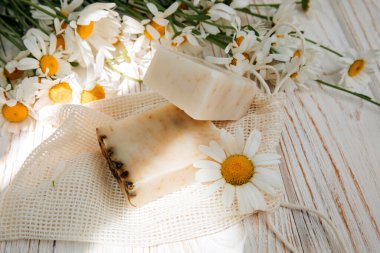 Doğal malzemelerden elde yapılan sabun, çeşitli otlar, papatya çayı. Sürdürülebilir kullanım kavramı, ahşap bir masada banyo ürünleri. Üst görünüm