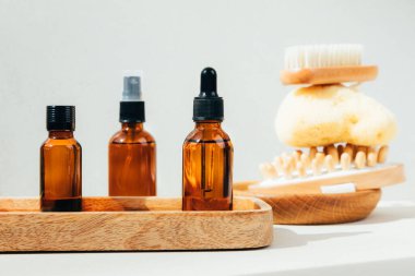 Doğal kozmetik seti. Yüz bakımlı kehribar şişeleri, beton zeminde banyo sıvısı ve doğal banyo süngeri. Ön görünüm