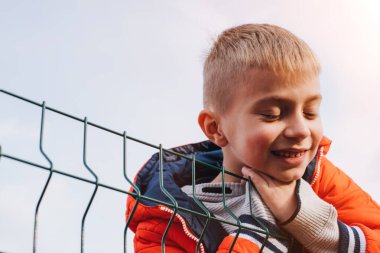 Stadyumda turuncu ceketli bir çocuk var. Sonbahar yürüyüşü. Gün batımında bir çocuğun portresi. Ön görünüm