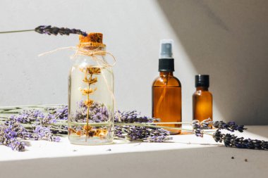 Açık arkaplanda lavanta yağı ve parlak güneş ışığı altında lavanta çiçekleri. Ön görünüm