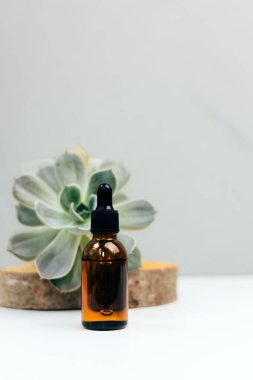 Doğal kozmetikler. Yüz bakımlı kehribar şişesi, beton arka planda banyo sıvısı ve yeşil sulu. Ön görünüm