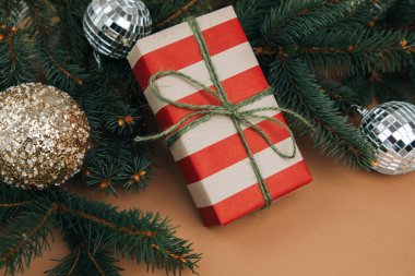 Noel, şenlikli bir geçmiş. Kahverengi arka planda kırmızı ve kahverengi kağıda sarılı hediyeler ve çam dalları. Üst görünüm
